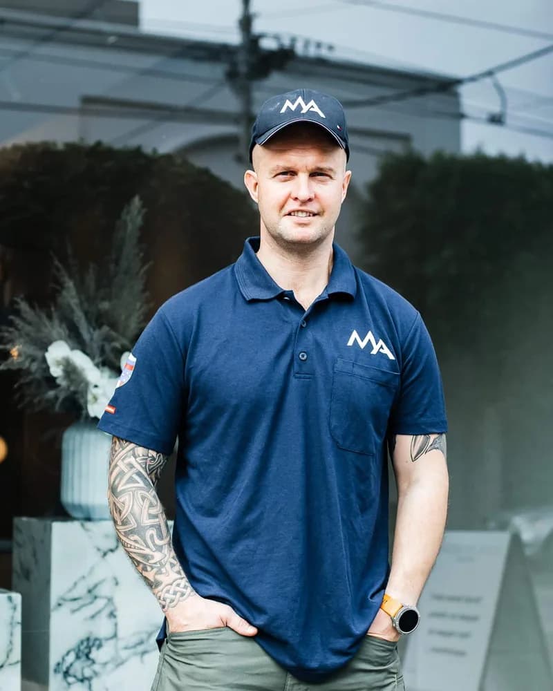 Max, microcement specialist, standing outside a shopfront in a navy polo shirt and cap